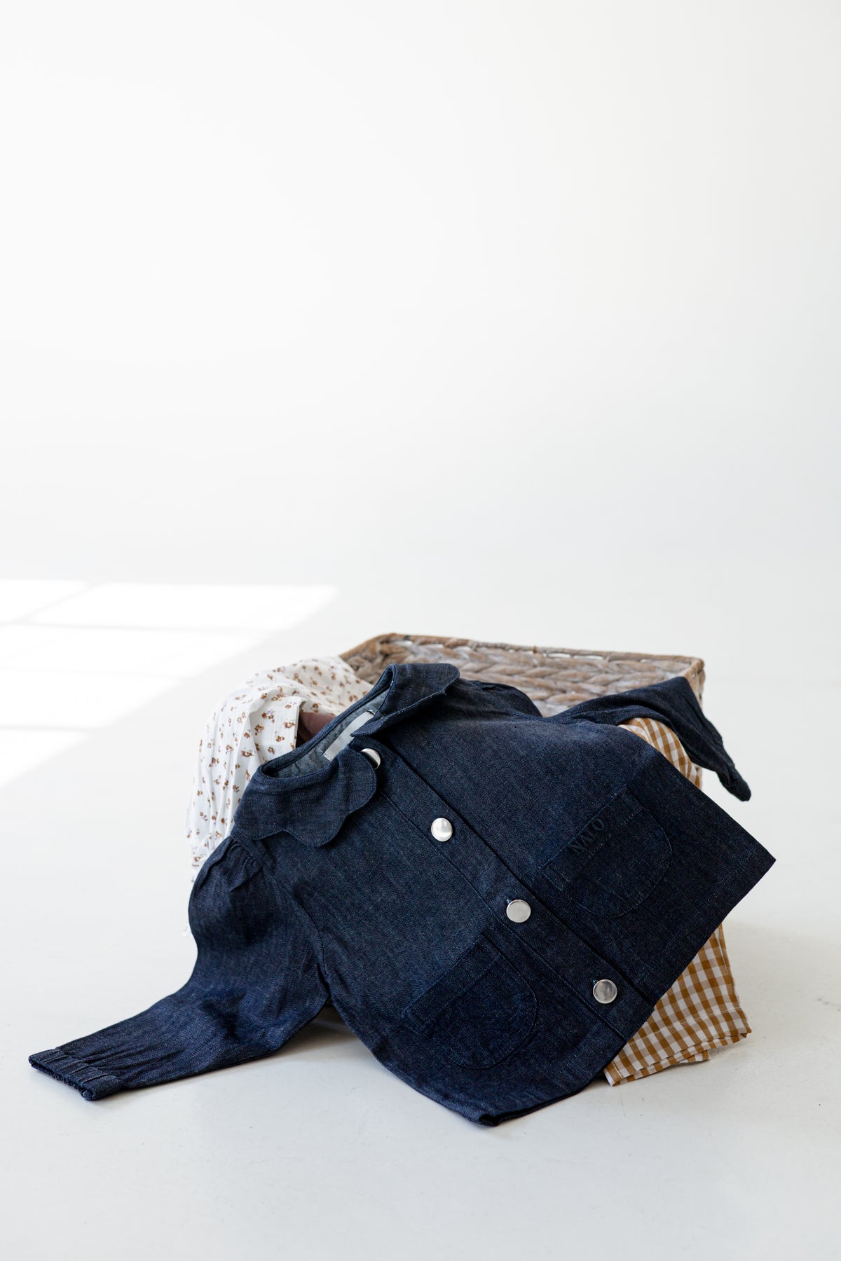 Baby denim jacket lying over a wooden box.